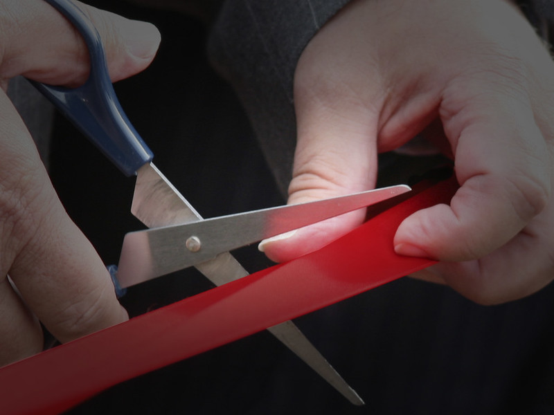 Pair of scissors cutting red tape